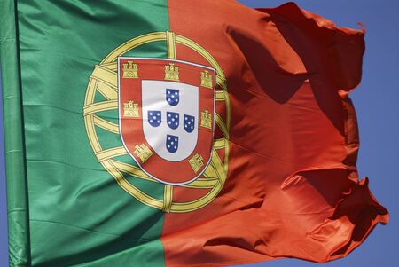 Portuguese flag blowing in the wind against blue skyの写真素材