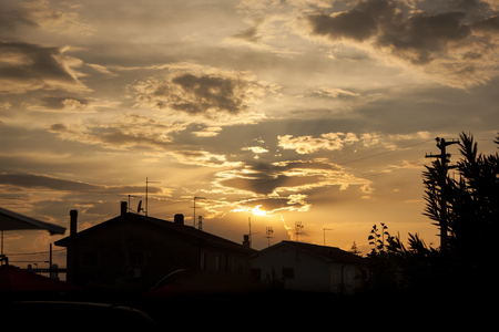 Sunset in a small Italian village, and highlight the silhouette of houses and elements that make up the landscape as a whole.の写真素材