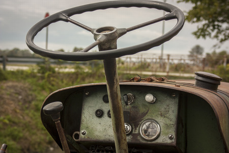 Details of the steering wheel and instrumentation of an old farm tractor nestled in the countryside during a work day.の写真素材