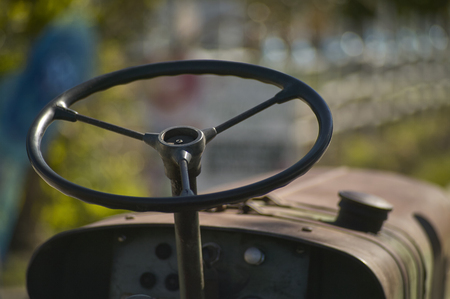 Details of the steering wheel and instrumentation of an old farm tractor nestled in the countryside during a work day.の写真素材