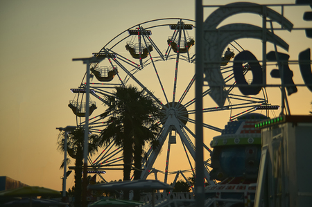View of a panoramic wheel with the sunset behind, taken in a moon park in a seaside resort.の写真素材