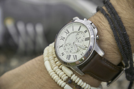 Detail of a vintage wristwatch worn by a boy with other bracelets, symbol of time passing. A great acession for a perfect outfit.の写真素材