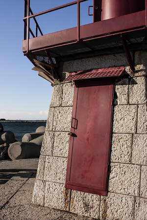 Red painted iron door belonging to the lighthouse in the dam of Sottomarina in Veneto Italy.の写真素材