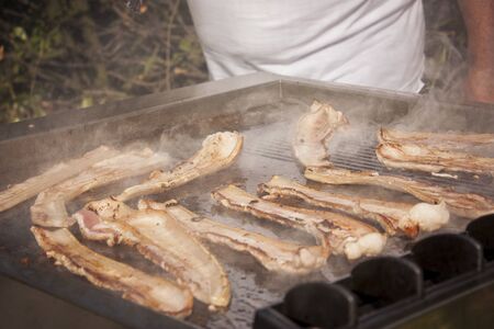 Crunchy bacon on the grill during preparation while cooking and roasting for lunch.の写真素材