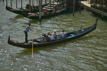 Gondolier resting on his gondola charged by some tourists taken from above.のeditorial素材