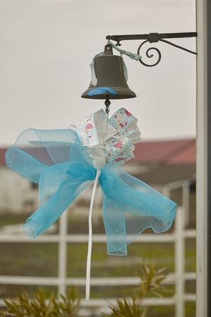 Blue bow hanging from a metal bell to symbolize the birth of a child, or to celebrate the ceremony of Catholic baptism.の写真素材