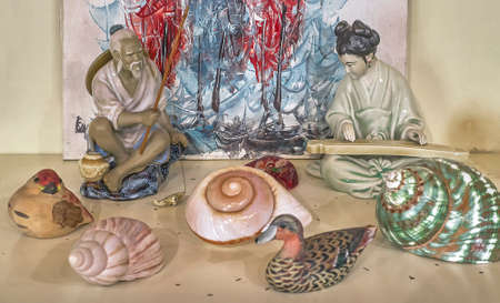 Collection and display of vintage oriental souvenirs on a wooden shelf of a piece of furniture in front view.の写真素材