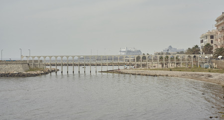 Pedestrian bridge with arches and columns on the water at Civitavecchia in Italy.の写真素材