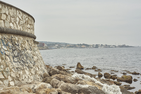 Detail of the pier with the rocks and the waves crashing on them.の写真素材