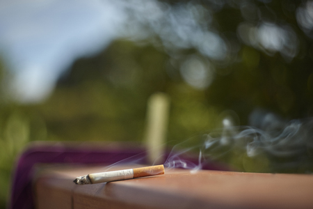 Cigarette lit on a wall with smoke coming out of the light breeze.の写真素材