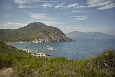 Natural inlet between the mountains and the sea in the south of Sardinia with the outline of a typical Mediterranean vegetation that grows spontaneously on the rocky walls.の写真素材