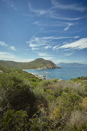 Vertical shot of the panorama of a natural bay in the south of Sardinia in Italy with the mountains overlooking the sea in broad daylight during the summer.の写真素材