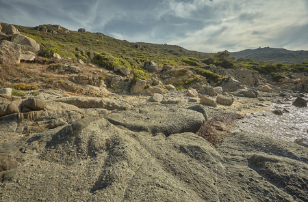 Background with a typical Mediterranean landscape formed by rocks, rocks and shrubbery on a beach in the summer.の写真素材