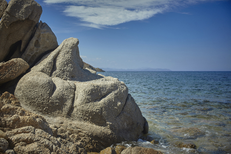 A particular rock with sinuous and undulating forms with the background of the azure and crystalline Mediterranean sea during the summer.の写真素材