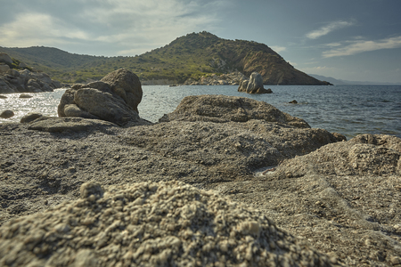 Background of a panorama including a rocky beach with the sea and the mountains full of Mediterranean vegetation in the background.の写真素材