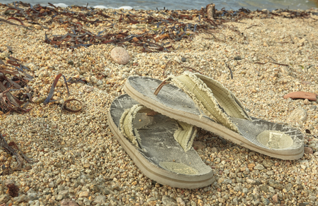 Pair of worn and worn flip-flops abandoned on the sand of the Mediterranean beach.の写真素材