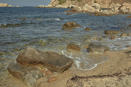 Some pebbles resting on the shore of the sea where the crystalline water meets with the sand of the sea.の写真素材