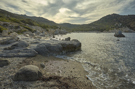 Wide-angle shot of a cliff typical of the landscapes of southern Sardinia with a wonderful beach at sunset.の写真素材