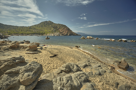 Beautiful Mediterranean beach typical of the coast of southern Sardinia taken over in summer. The beach, the rocks and the mountains behind blend in a wonderful panorama of amazing beauty.の写真素材