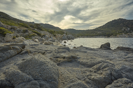 Beautiful Mediterranean beach typical of the coast of southern Sardinia taken over in summer. The beach, the rocks and the mountains behind blend in a wonderful panorama of amazing beauty.の写真素材
