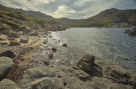 Beautiful Mediterranean beach typical of the coast of southern Sardinia taken over in summer. The beach, the rocks and the mountains behind blend in a wonderful panorama of amazing beauty.の写真素材