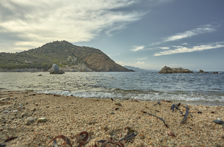 Shooting from the ground of a typical central Mediterranean beach: magnificent seascape with the sand of the beach in the foreground with the sea and the background mountains.の写真素材