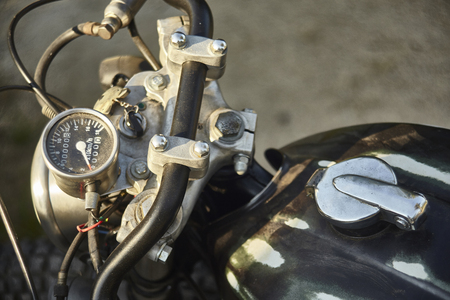 Detail of the handlebars and the speedometer of a vintage black motorcycle, with visible chrome and control details.の写真素材