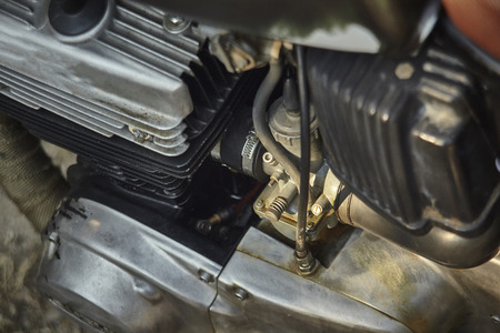 Detail of some components of a vintage motorcycle engine with emphasis on the carburetor and the intake box, right next to the engine head.の写真素材