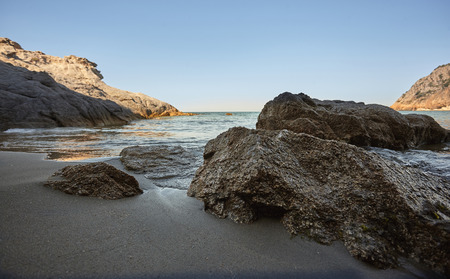 Beautiful seascape with wide-angle shot of the exit from a cave with the sea and the shore of the beach in the foreground, the sea to the horizon in the background and to the right a rock that merges with the sea. Symbol of vacations and natural beach.の写真素材