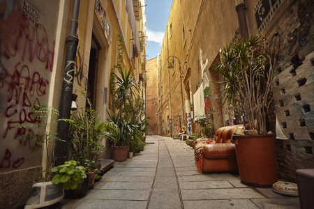 Characteristic alley of the city of Cagliari in Sardinia with an outdoor sofa and many plants decorate the street.の写真素材