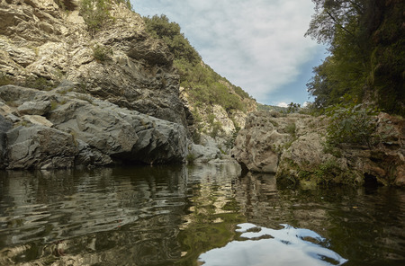 View from the middle of a stream that flows in the middle of a mountain with the rocky cliffs alongside.の写真素材