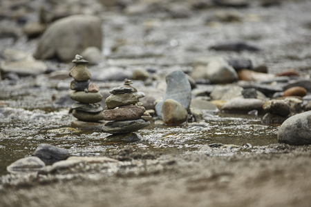 Several stacks of rocks interrupt the flow of water in the streamの写真素材