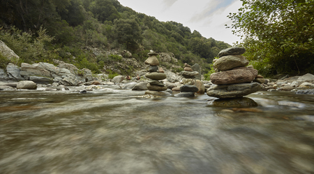 Mountain stream with stacks of rocks and water movement with silky effect created with long exposure.の写真素材
