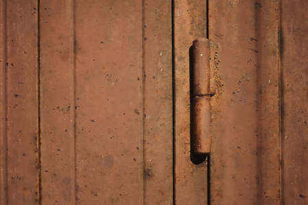 Detail of the hinge of a brown metal door, rusted and ruined by weather and bad weather. Horizontal shot.の写真素材