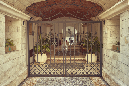 Entrance gate in wrought iron towards a luxurious closed house.の写真素材
