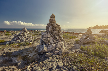 Stacks of zen rocks in the middle of the rocky coast of Puerto Aventuras in the Mayan Riviera in Mexico at sunset.の写真素材