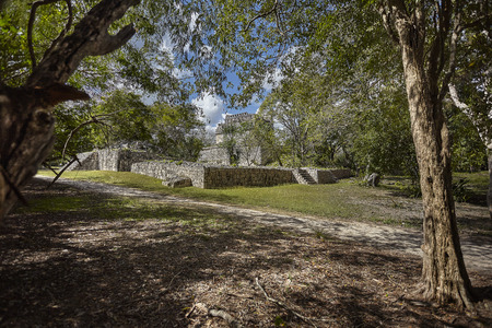 Entire building filtered by vegetation and trees belonging to the archaeological complex of Chichen Itza in Mexicoの写真素材