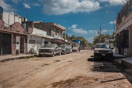 View of a street of Tulum in Mexico with unpaved roads and some vehicles parked at the side.のeditorial素材