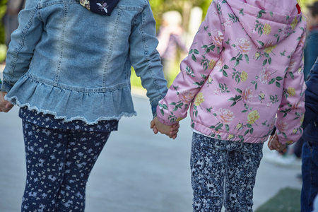 Couple of children shot from behind holding hands