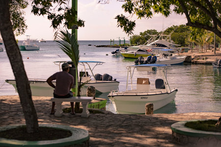 BAYAHIBE, DOMINICAN REPUBLIC 23 DECEMBER 2019: Man sitting on the bench looks at the sea from the port of Bayahibe in Dominican Republicのeditorial素材