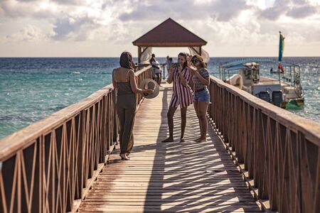 DOMINICUS, DOMINICAN REPUBLIC 6 FEBRAURY 2020: Girls take a picture with their smartphone on the Dominicus pier at sunsetのeditorial素材