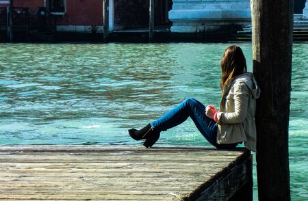 Girl sitting near the river on pierの写真素材