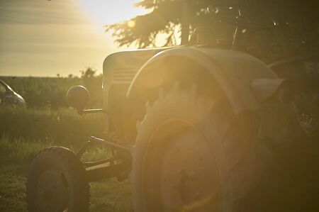 Agricultural tractor at sunset evocative image of work in the fieldsの写真素材