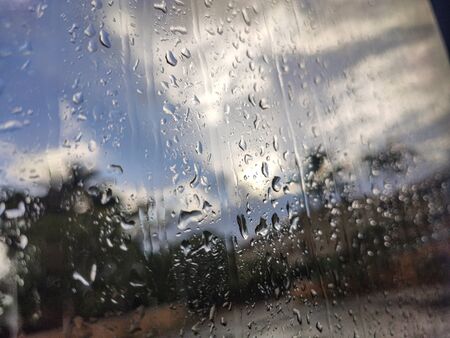 Drops on the window with natural landscape behind the windowの写真素材