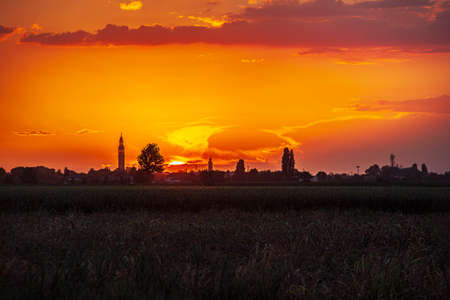 Sunset in a landscape with bell tower, trees and countrysideの写真素材