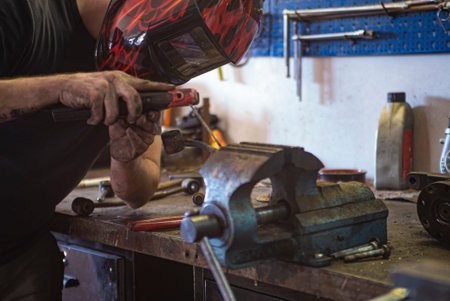 Detail of Man welds metal in a workshop