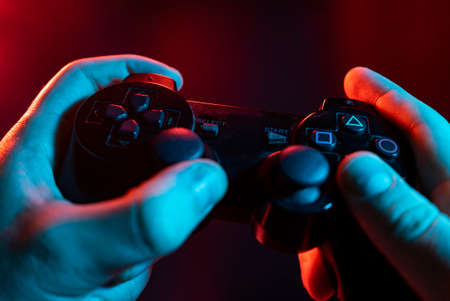 Close up of male hands playing the video game at night with joystick in handsの写真素材