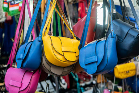 Many leather purse bags vibrant colors hanging on display in shopping street marketの写真素材