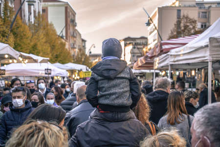 ROVIGO, ITALY 26 OCTOBER 2021: Child sitting on daddy's shoulders at a street marketのeditorial素材