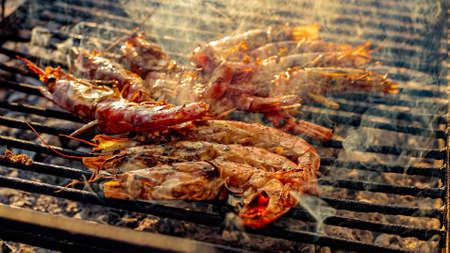 Grilled shrimp on a grill with charcoal grill. Close-up of shrimps being fried in oil panの写真素材